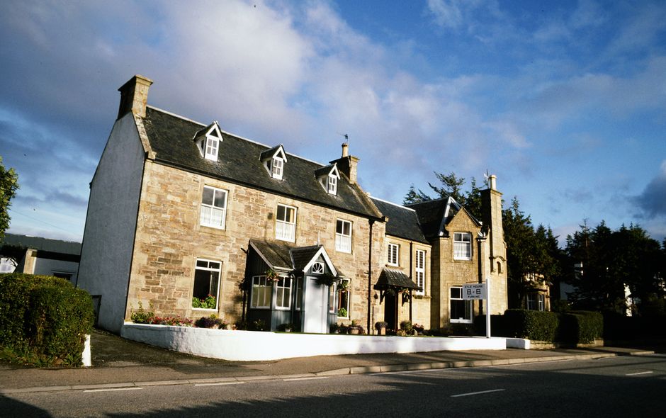 Charming Scottish stone bed and breakfast with rustic architecture under a bright blue sky.